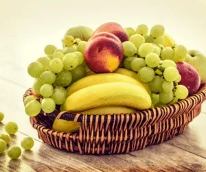 Cesta de verguinha com fruta com bananas, pessegos e uvas