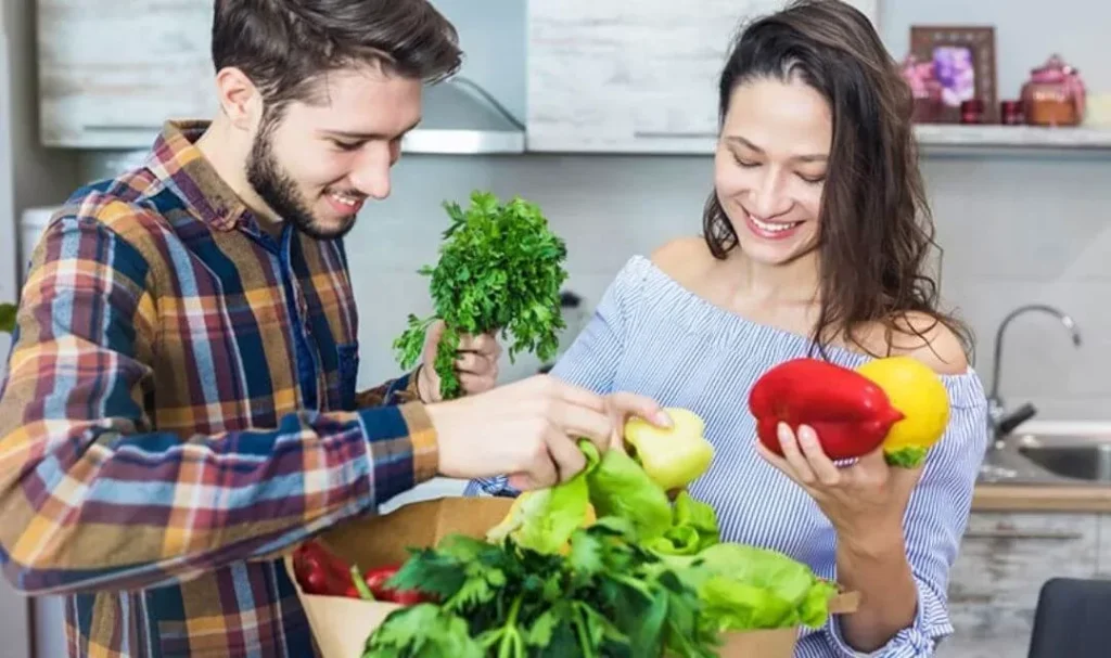 Casal a rir e a arrumar as compras de alimentação saudável